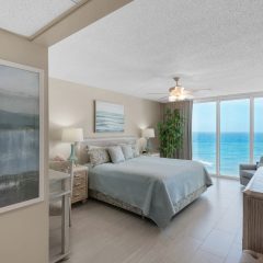 Elegant master suite with king sized bed and wall of windows that capture stunning Gulf views