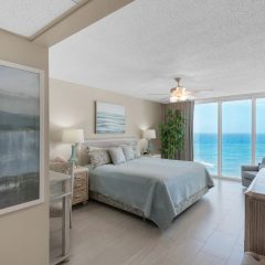 Elegant master suite with king sized bed and wall of windows that capture stunning Gulf views